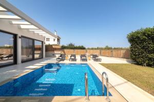 a swimming pool in the backyard of a house at Oresteia Exclusive Villa, a Sublime Retreat, By ThinkVilla in Tragaki