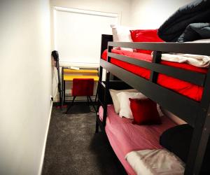 WindermereLucas One 2-bedroom apartment NBN Pets的一间卧室配有两张双层床,铺有红色床单
