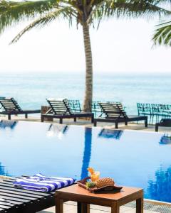 einen Pool mit Stühlen und einem Tisch am Meer in der Unterkunft Peacock Beach Resort and Spa in Hambantota