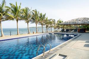 uma piscina com palmeiras e o oceano em Peacock Beach Resort and Spa em Hambantota