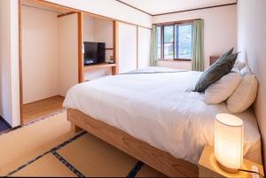 a bedroom with a large white bed and a window at Iimori Vista in Hakuba