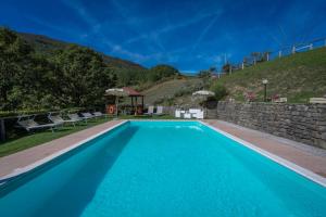een blauw zwembad met een stenen muur bij La Vecchia Fornace - Abetone, authentic farmhouse with private pool in Pian degli Ontani
