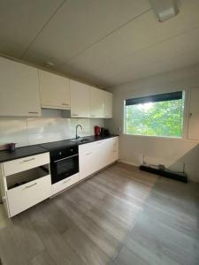 a large kitchen with white cabinets and a window at Kotimaailma - Hostel Kivikkotie in Vantaa