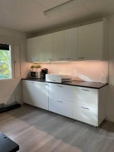 a kitchen with white cabinets and a counter top at Kotimaailma - Hostel Kivikkotie in Vantaa