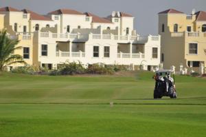 a golf cart driving on a golf course at Hala Holiday Homes - Al Hamra Village, RAK in Ras al Khaimah