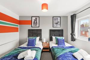 Stylish 4 Bed House in Yorkshire - Sleeps 9 في Hickleton: سريرين في غرفة بها برتقال وزرق