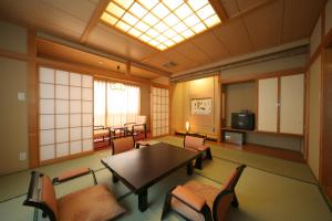 een kamer met een tafel en stoelen en een raam bij Oiwakeya Ryokan in Matsumoto