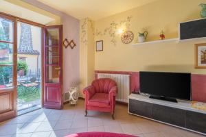 een woonkamer met een tv en een rode stoel bij La Vecchia Fornace - Abetone, authentic farmhouse with private pool in Pian degli Ontani