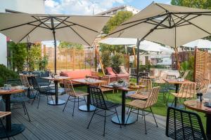 a patio with tables and chairs and umbrellas at Ibis Alès Centre Ville in Alès