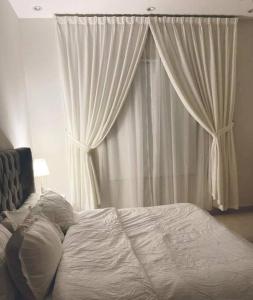 a bed in front of a window with white curtains at شقة فاخرة (مدخل خاص - دخول ذاتي) in Riyadh