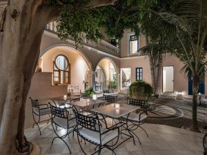 un patio con mesas, sillas y palmeras en Casa Delfino Hotel & Spa, en La Canea