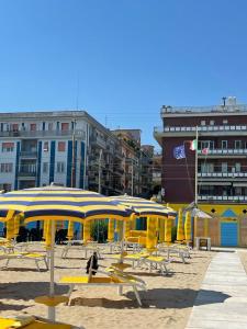 una playa con sombrillas amarillas, sillas y edificios en appartamento fronte mare, en Falconara Marittima