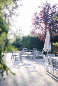un grupo de mesas y una sombrilla y sillas blancas en La villa des Crénées, en Héron
