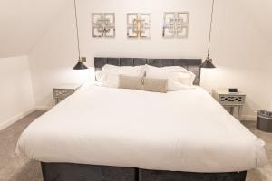 a bedroom with a large white bed with two lamps at Elms Cottage in Spalding