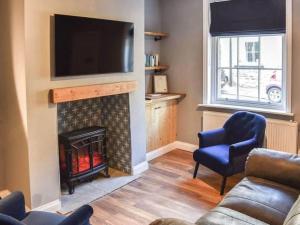 uma sala de estar com lareira e televisão de ecrã plano em Cosy 2 bedroom Cottage in a World Heritage Village em Shipley