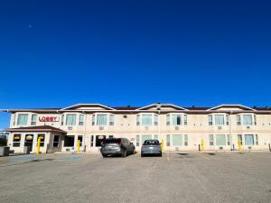 a hotel with two cars parked in a parking lot at Western Budget Motel #3 Whitecourt in Whitecourt