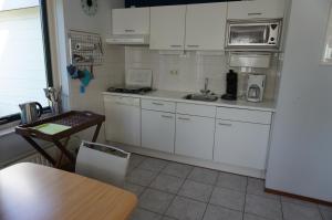 a kitchen with white cabinets and a table in it at Kustverhuur, Park Schoneveld, Stern 233 in Breskens +14 photos