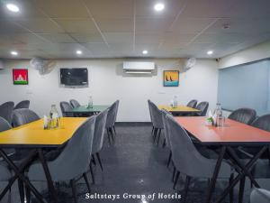 a conference room with tables and chairs and a screen at Saltstayz Hotel Huda City Centre in Gurgaon