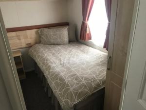 a small bed in a small room with a window at 3 Bedroom Self Catering Static Caravan in Steps