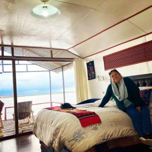 una mujer sentada en una cama en un dormitorio en Sol del TITICACA lodge, en Uros
