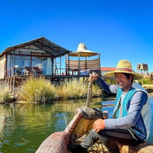 a man in a straw hat riding on a boat in the water at Sol del TITICACA lodge in Uros