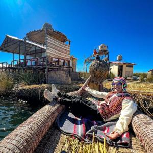 a woman sitting on the ground next to a basket at Sol del TITICACA lodge in Uros