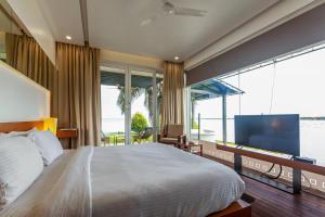 a bedroom with a large bed and a large window at StayVista at The Rain - River Villa with Infinity Pool in Alleppey