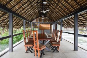 un comedor con una mesa larga y sillas en StayVista at The Rain - River Villa with Infinity Pool en Alleppey