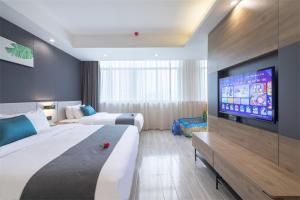 a hotel room with two beds and a flat screen tv at Thank Inn Plus Shaoguan Qujiang District Maba in Shaoguan