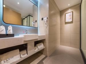 y baño con lavabo, espejo y ducha. en LanOu Hotel Wuxi Anzhen East High-Speed Railway Station en Wuxi