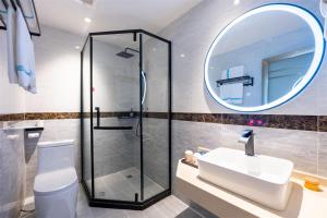 a bathroom with a shower and a sink and a mirror at Junyi Hotel Wuhan Liuduqiao Subway Station in Wuhan