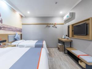 a hotel room with two beds and a flat screen tv at Junyi Hotel Hefei South High-Speed Railway Station in Hefei