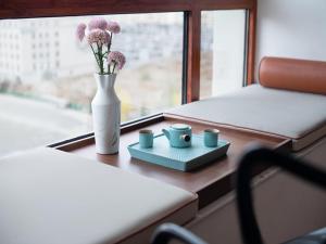 a vase with flowers and three cups on a window sill at LanOu Hotel Lhasa Municipal Government Tibet University in Lhasa