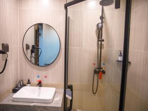 a bathroom with a sink and a shower with a mirror at Thank Inn Hotel Changsha Ningxiang Avenue High-Speed Railway Station in Ningxiang