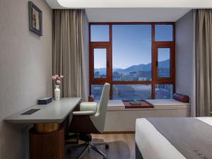 ラサ市にあるLanOu Hotel Lhasa Municipal Government Tibet Universityのデスク、ベッド、窓が備わるホテルルームです。