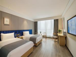 a hotel room with two beds and a television at LanOu Hotel Taikoo Li Night Market Kuqa City in Kuqa