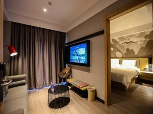 a hotel room with a bed and a flat screen tv at Thank Inn Plus Baotou Kundulun District University of Science and Technology in Baotou