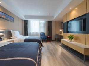 une chambre d'hôtel avec deux lits et une télévision à écran plat dans l'établissement LanOu Hotel Wuxi Anzhen East High-Speed Railway Station, à Wuxi