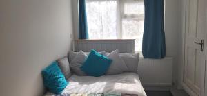- un canapé avec des oreillers bleus et blancs devant une fenêtre dans l'établissement Stadium Nook, à Wembley