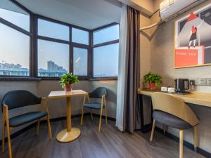 Habitación con 2 mesas, sillas y ventana en Thank Inn Plus Linxia Bafang Shisanxiang, en Linxia