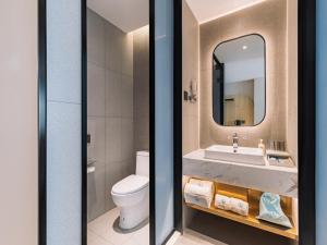 ein Badezimmer mit einem Waschbecken, einem WC und einem Spiegel in der Unterkunft LanOu Hotel Qingdao West Station Haixi Road in Qingdao
