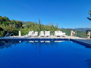 a group of white chairs sitting next to a swimming pool at Casa Varanda do Geres in Terras de Bouro