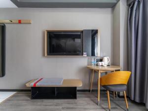 a room with a table and a tv on a wall at Thank Inn Plus Kashgar Ancient City Pedestrian Street in Kashgar