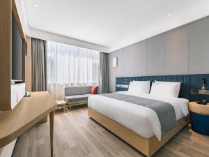 ein Hotelzimmer mit einem großen Bett und einem Sofa in der Unterkunft LanOu Hotel Qingdao West Station Haixi Road in Qingdao