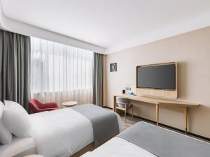 ein Hotelzimmer mit 2 Betten und einem Flachbild-TV in der Unterkunft LanOu Hotel Qingdao West Station Haixi Road in Qingdao