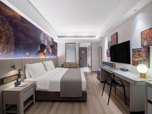 拉薩的住宿－拉萨市政府西藏大学兰欧国际酒店，酒店客房设有一张大床和一张书桌。