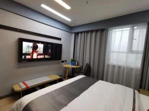 um quarto com uma cama e uma televisão na parede em Thank Inn Plus Korla Saybag Market em Korla