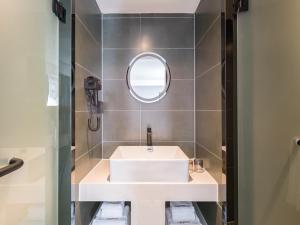 a bathroom with a white sink and a mirror at Feronia Hotel Beijing Bird's Nest Datun Road in Beijing