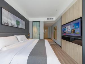een slaapkamer met een groot bed en een flatscreen-tv bij Thank Inn Linyi Jiaxing Fruit Market in Linyi