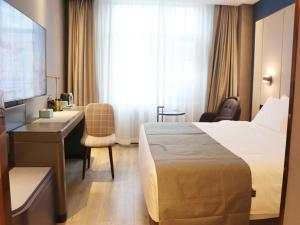LanOu Hotel Longjiang Road Shigatse في شيغاتسي: غرفة في الفندق مع سرير ومكتب